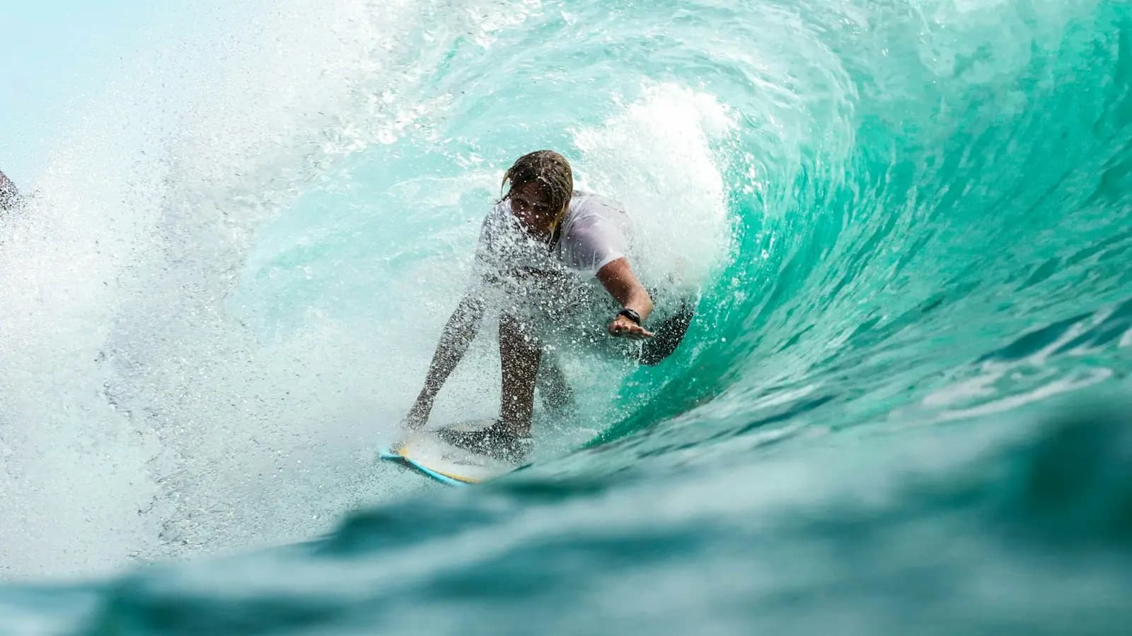 A surfer riding along the face of a long wave peeling past a rocky point